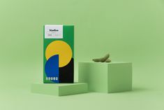 a small bird sitting on top of a green box next to it's packaging