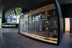 a display case filled with lots of trophies on top of a tiled floor next to a wall