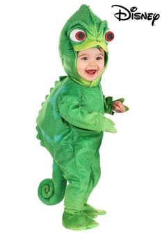 a baby in a green dinosaur costume standing on one leg and smiling at the camera