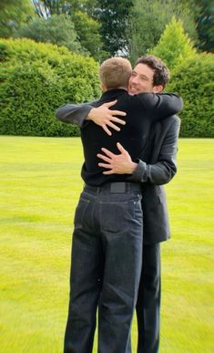 two men hugging each other in the grass