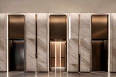 the elevators are lined up against the wall in this modern style building with marble walls and flooring