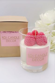 a candle with raspberries in it next to a box