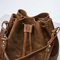 Leather Bucket Satchel For On-the-go, Brown Bucket Bag For On-the-go, Leather Crossbody Bucket Bag For On-the-go, Leather Bucket Shoulder Bag With Dust Bag, Large Capacity Shoulder Drawstring Bag For Everyday Use, Everyday Leather Hobo Bag With Dust Bag, Leather Large Capacity Pouch Bucket Bag, Large Capacity Leather Pouch Bucket Bag, Leather Bucket Bag With Large Capacity