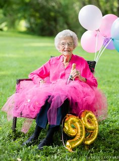 an elderly woman sitting in a chair with balloons and the number twenty nine on it