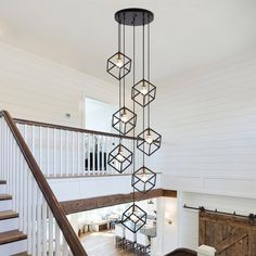 a large chandelier hanging from the ceiling in a living room next to stairs