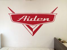 a bed room with a neatly made bed and a wall sticker that says alden