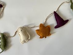 several felt animals hanging from a string on a white surface with green and purple leaves