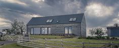 a house sitting on top of a lush green field next to a wooden fence covered in grass