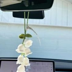 a laptop computer sitting on top of a desk in front of a car window with flowers hanging from it