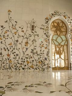 an intricately designed wall with flowers and vines in the middle is painted on white tiles