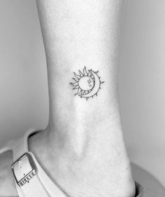 a small sun and moon tattoo on the side of the ankle, with an arrow in the center