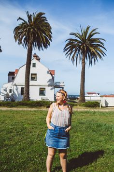 a woman standing in the grass near some palm trees