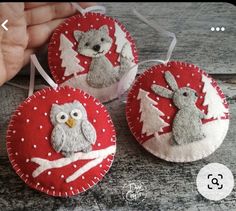 three felt ornaments with animals on them are being held by a person's hand