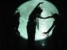 the silhouettes of two people dancing in front of a full moon