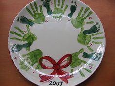 a white plate with handprints on it and a red ribbon around the rim