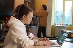 a woman sitting at a table using a laptop computer