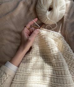 a woman is knitting on a blanket with her hands