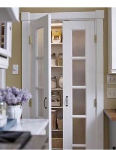 an open pantry door in a kitchen next to a counter top with baskets on it