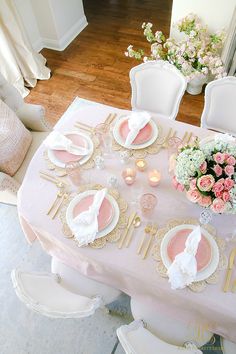 the table is set with pink and white plates, napkins, and silverware