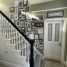 a staircase with many pictures on the wall and framed photos on the wall above it