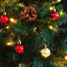 a christmas tree with red and gold ornaments on it's branches, lit up by lights