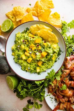 a plate with shrimp, guacamole and tortilla chips