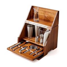 an open wooden box with utensils and cups in it on a white background