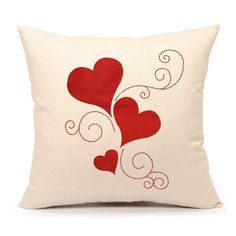 a white pillow with red hearts and swirls on the front, sitting against a white background