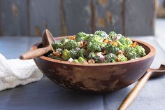 a wooden bowl filled with broccoli on top of a table