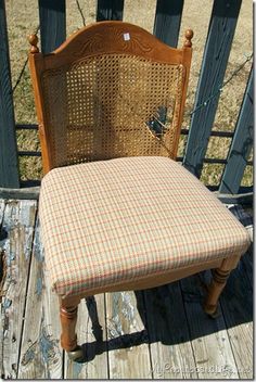 an old chair with a plaid seat cover on it's back sitting on a wooden deck