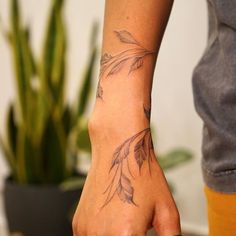 a person with a tattoo on their arm holding a doughnut in front of a potted plant