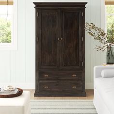 a living room with a white couch and wooden armoire