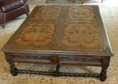 an ornately decorated coffee table sits in the middle of a living room with leather chairs