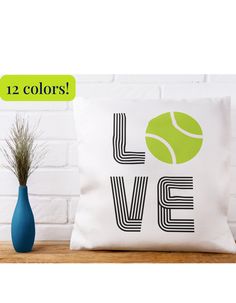 a white pillow with the words love and a tennis ball on it next to a blue vase