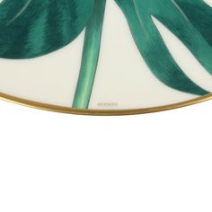 a green leaf on a white plate with gold trim