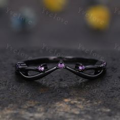 two black rings with pink stones on them sitting on a stone surface next to each other