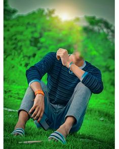 a man sitting in the grass with his hand on his face