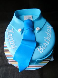 a blue birthday cake with a tie on it's top and the words happy birthday written in white