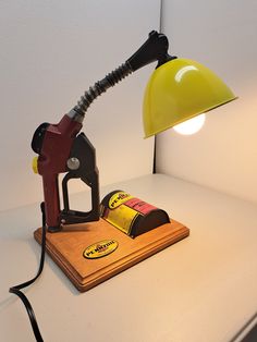 a gas pump sitting on top of a table next to a yellow light and a can