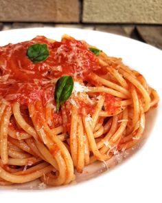 a plate of spaghetti with sauce and basil garnished with parmesan cheese