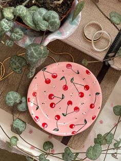 a pink plate sitting on top of a wooden table next to succulents