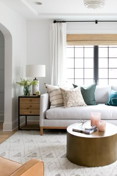 a living room with white furniture and pillows