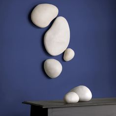 three white rocks sitting on top of a table next to a blue wall and a black desk