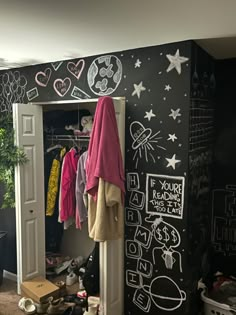 a closet with chalk drawings on the wall and clothes hanging from it's doors