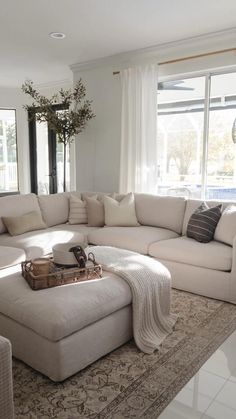 a living room with a large sectional couch and coffee table in front of two windows