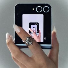 a woman's hand holding an electronic device with her fingers on the phone screen