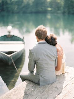 a man and woman sitting on a dock next to a boat