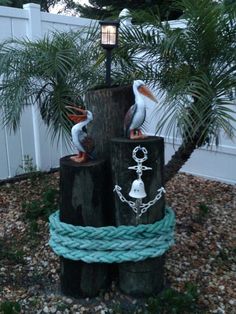 two pelicans sitting on top of a tree stump with ropes around it and a lamp in the background