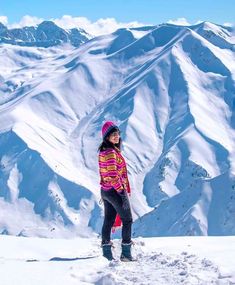 a woman standing on top of a snow covered slope