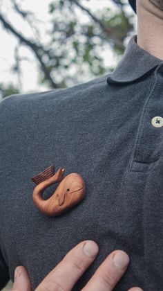 a close up of a person wearing a polo shirt with wooden buttons on his chest